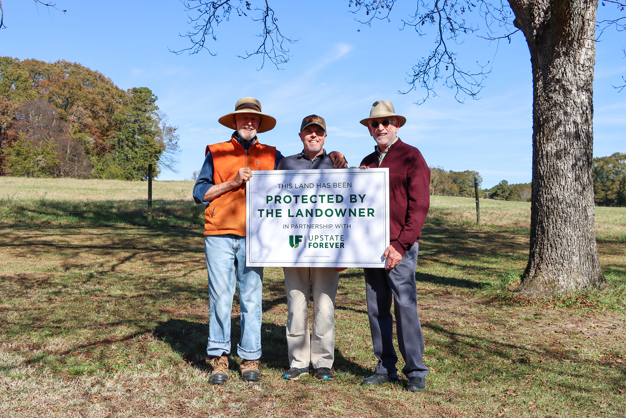 Snow Hill Farm landowners Ron and Jim King celebrate the protection of their family's 311-acre property with UF Land Conservation Manager Chris Starker (center).